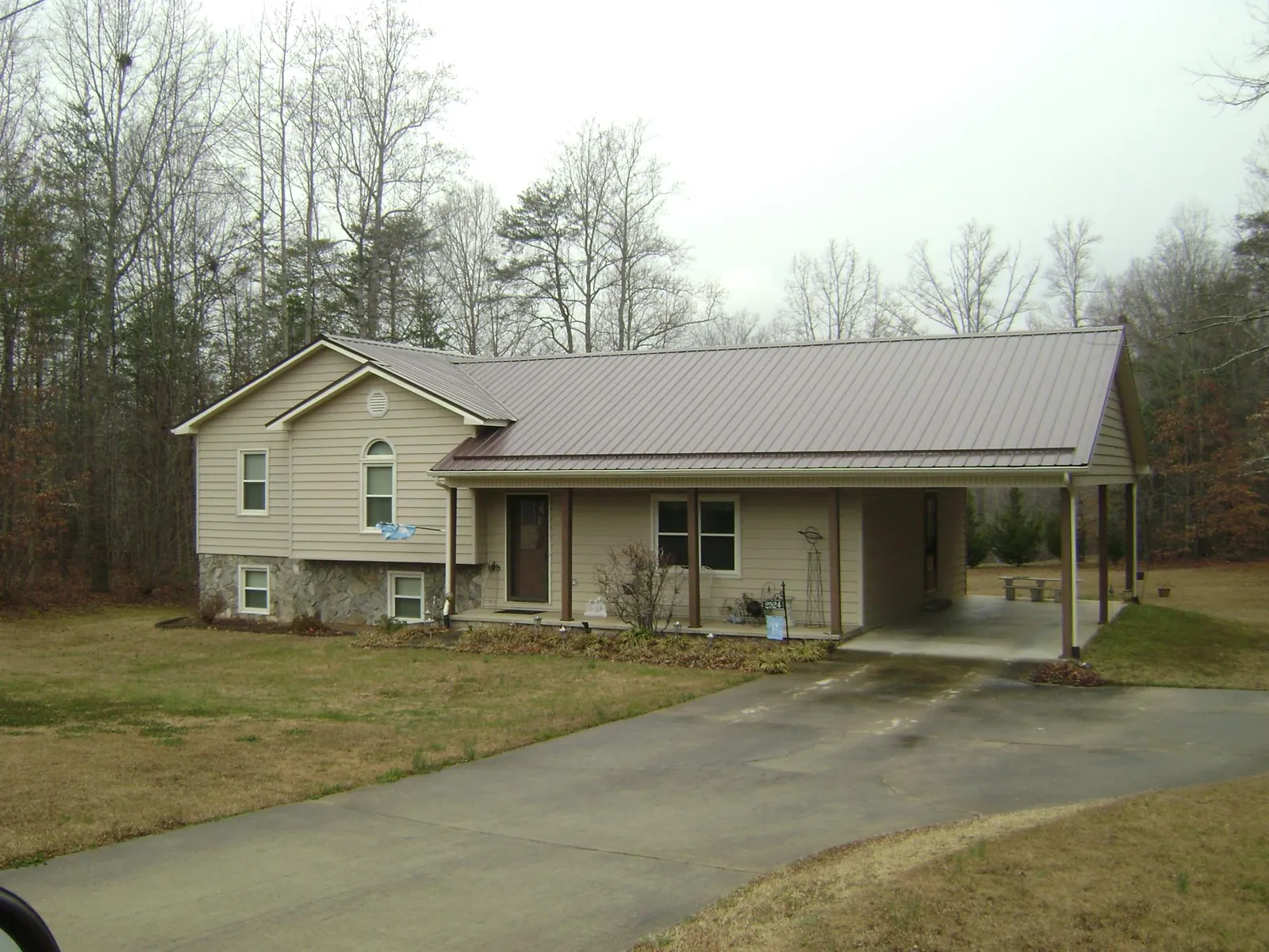 Brown metal roof on a tan split level home with an attached carport in Silver City